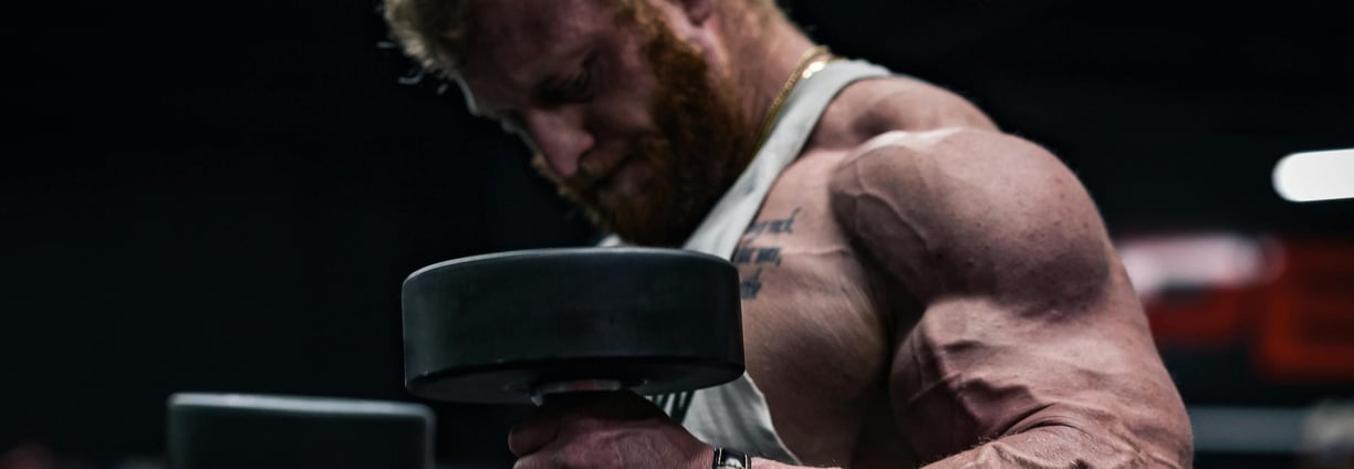 Muscular man lifting heavy dumbbells in a gym