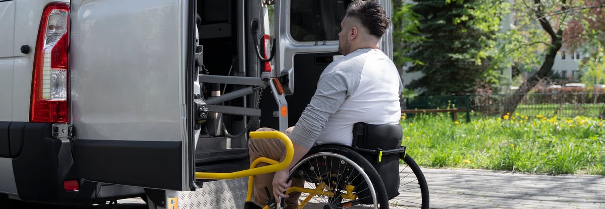 a man in a wheelchair wheel chair in front of a NEMT van