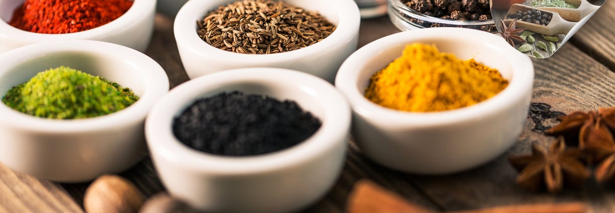 Various herbs and spices in white bowls