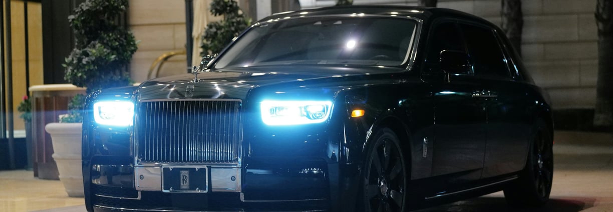 Front side image of a black Rolls Royce parked upon a pavement space
