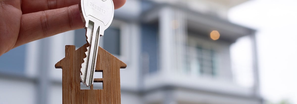 a person holding a keychain with a house keychaik