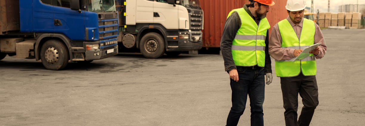two men in safety vests standing in front of a truck
