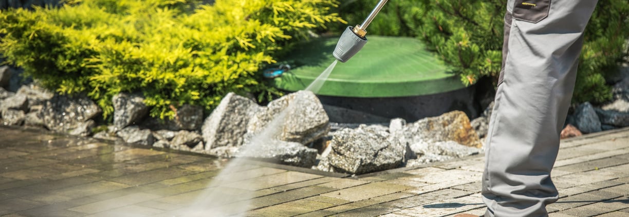 A man using a powerful pressure washer to clean a sidewalk