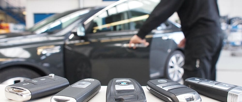 a man standing in front of a car with a bunch of keys