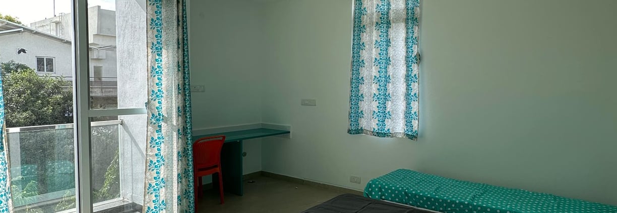 Spacious twin-sharing PG room in Banglore with a balcony, modern furniture, A/C and luxury.