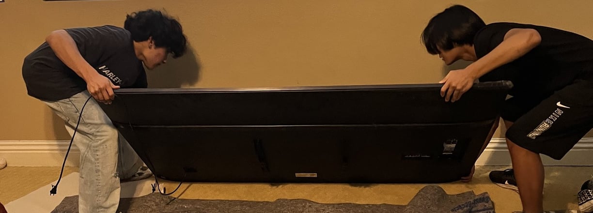 TwoTwo people carefully carrying a TV during a move.
