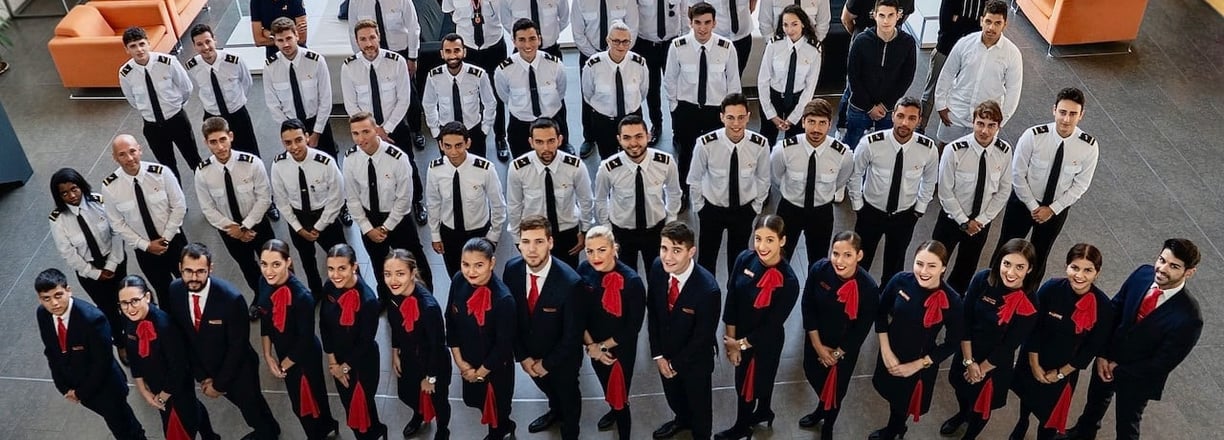 Diverse group of aviation students in uniforms reviewing flight plans in a classroom