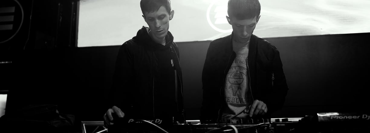 Twins brothers standing in front of a stage with a large screen