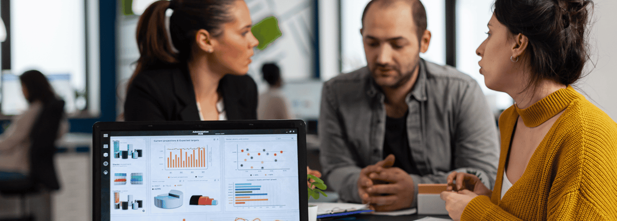 Team discussing data insights with graphs and charts displayed on a laptop.