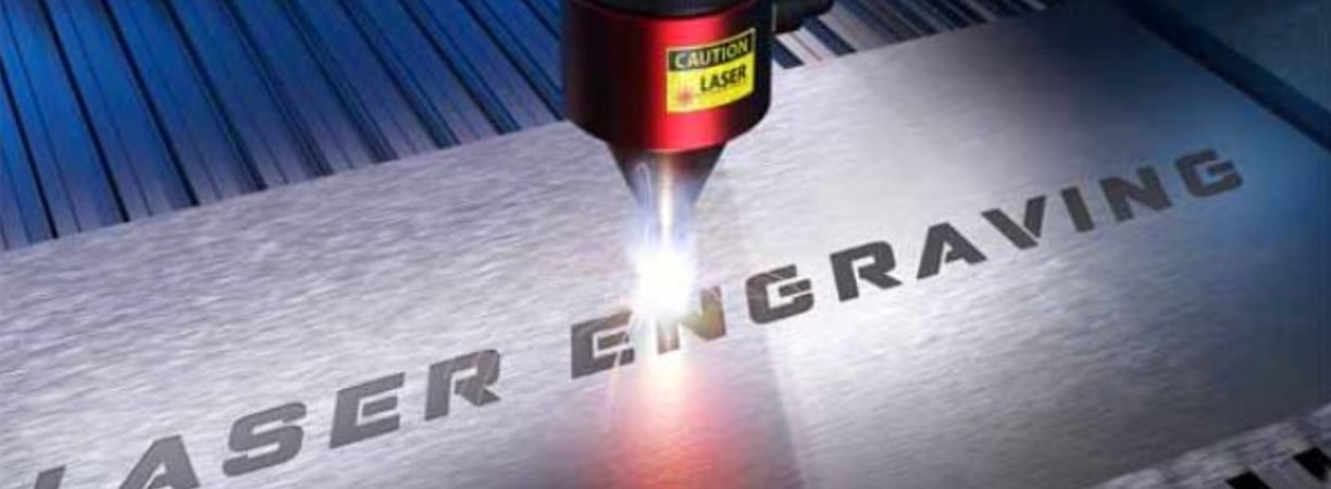 Una máquina de grabado láser en el proceso de grabado de una placa de metal.