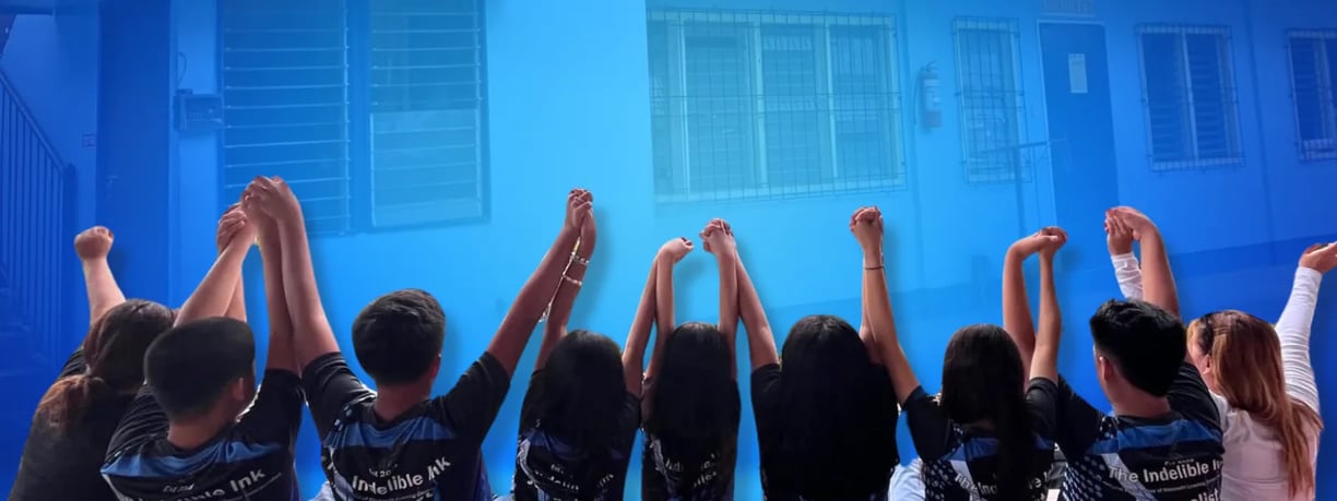 SLC students raising hands in triumph before school building, symbolizing unity, pride, and celebration.
