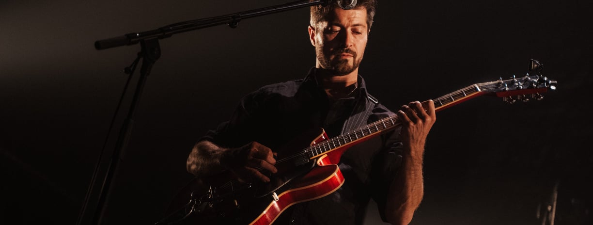 a man playing a Gibson red guitar in a concert