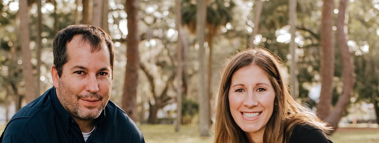 a man and woman sitting on a bench in a park