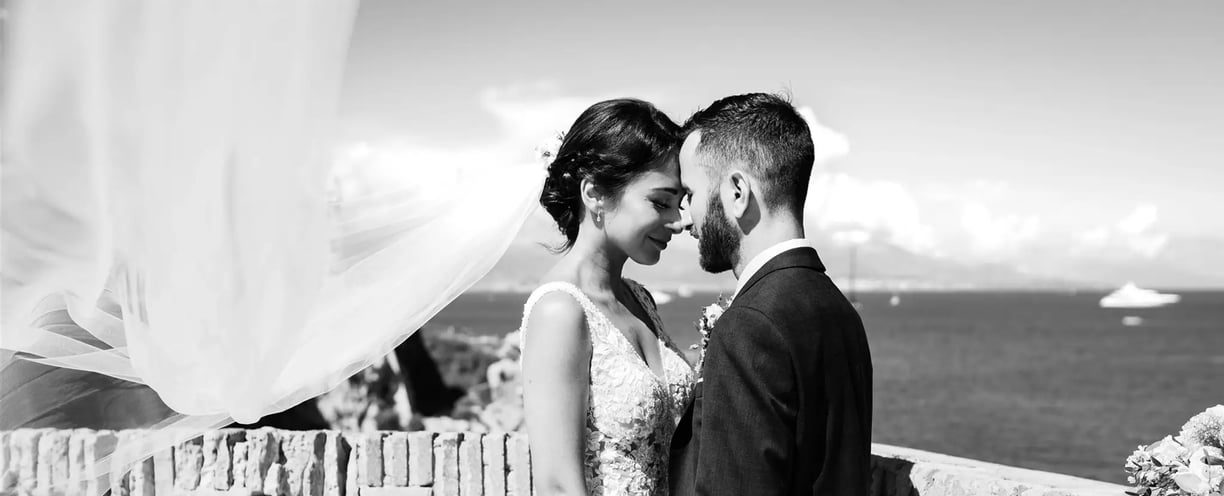 Black and white wedding photo with bride’s veil flying by the sea – BonjourMrsBride