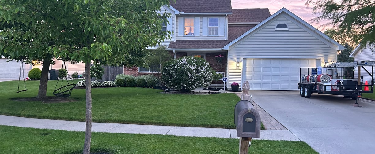 a beautiful, pressure washed home with power washing equipment in driveway during a sunrise 