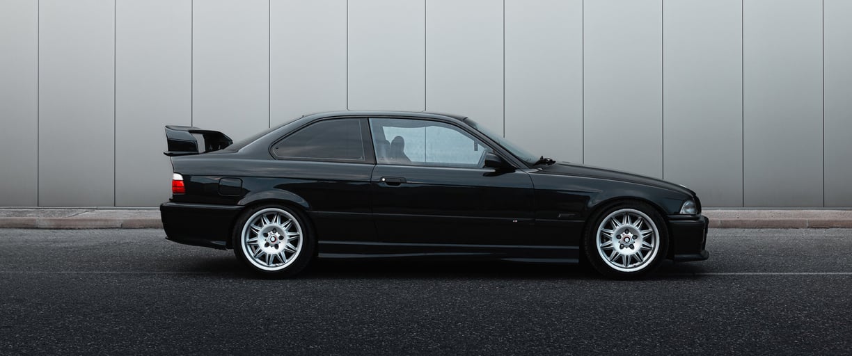 a black bmw m3 e36 parked in front of a building