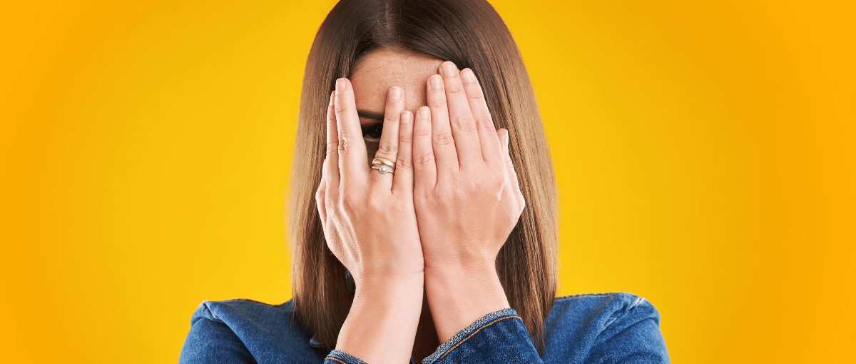 Femme qui se cache le visage avec ses mains. Manque de confiance en soi.