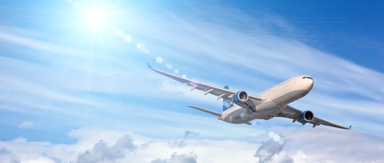 a plane flying in the sky with a bright sun shining on the clouds