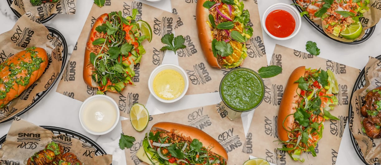 a flatlay of lots of sexy buns on a table, garlic bread, sauces all very colourful