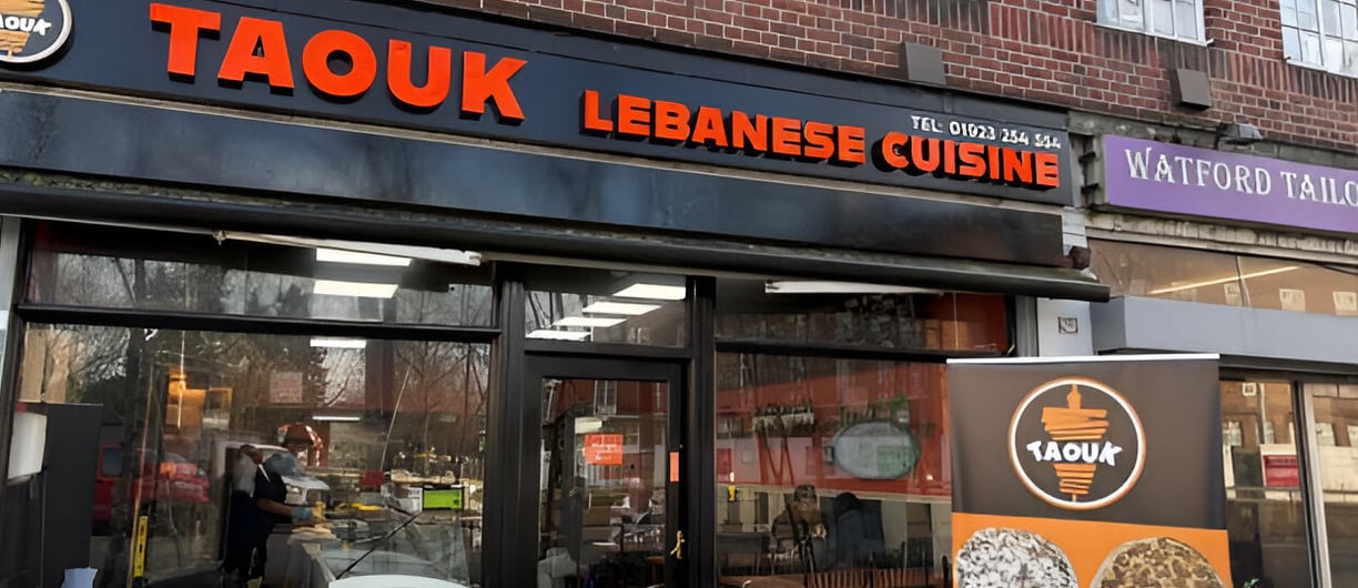 Taouk Watford restaurant logo displayed on a sign outside the building in Watford.