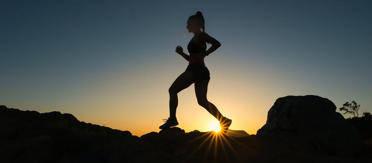 a woman running on a rocky mountain trail