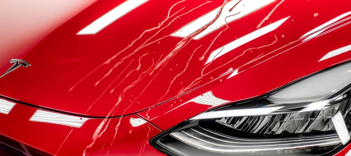 a red tesla detailing car with a shiny ceramic coating hood and a shiny cleaned clear headlights