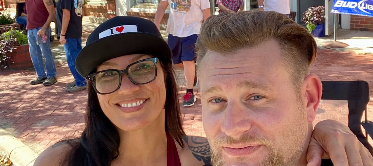 woman with her arm over mans shoulder smiling and taking a photo