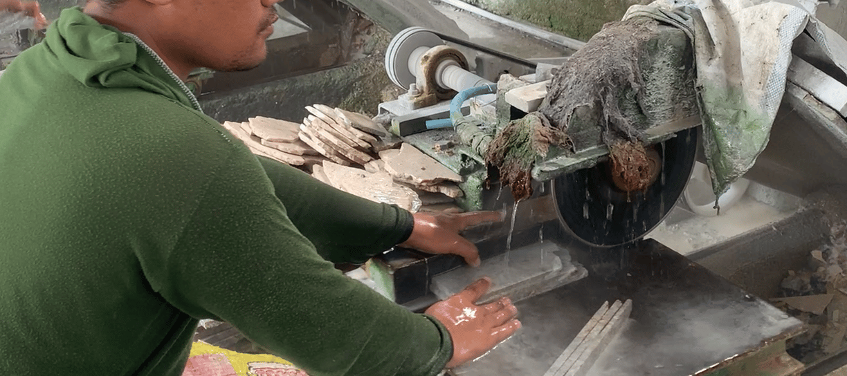 Workers are cutting natural stone to make mosaics