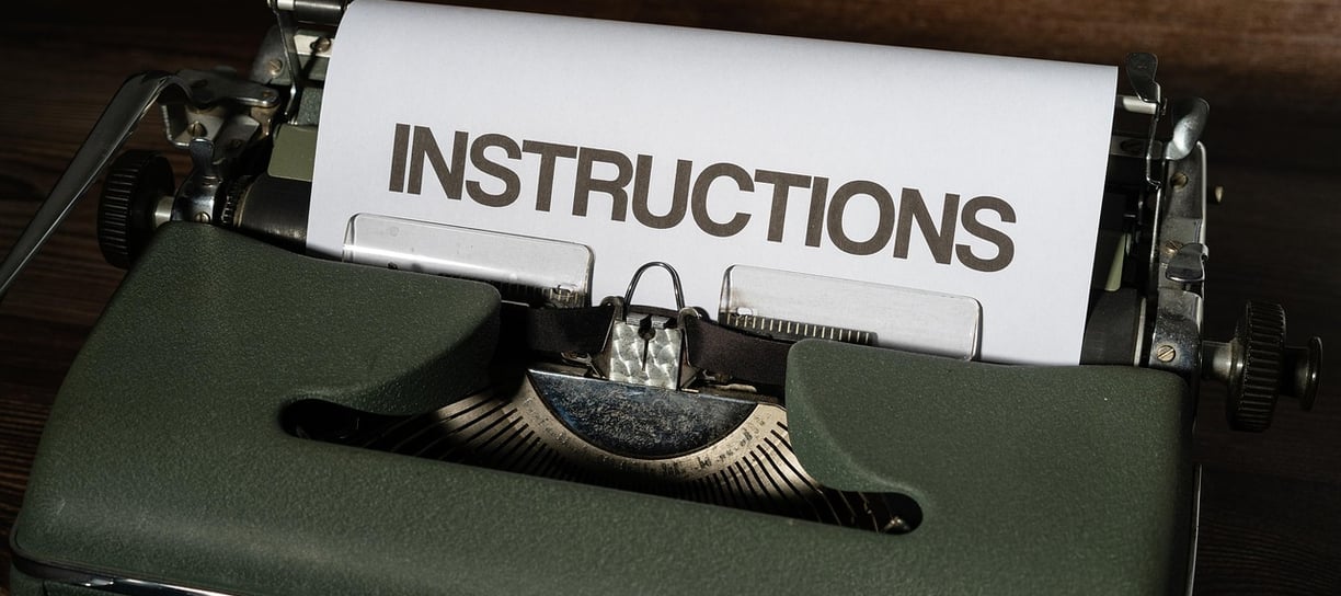 Zielona maszyna do pisania z kartka z napisem INSTRUCTIONS