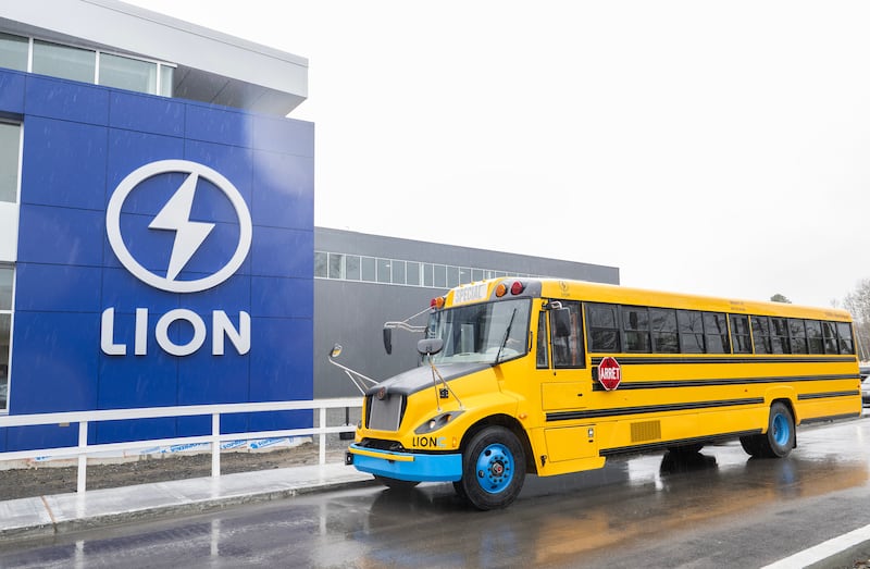 a yellow school bus parked in front of a lion