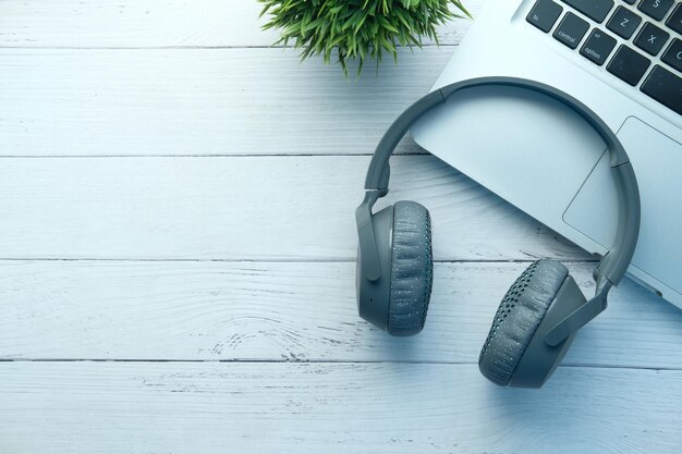 a laptop and headphones on a desk with a plant in the background, working on a transcription