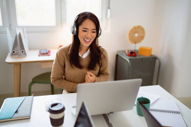 a woman with headphones at a laptop, engaged in an intensive language course with her tutor