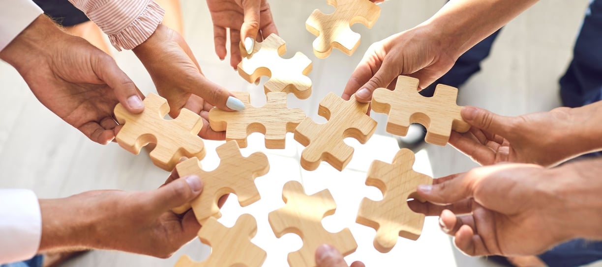 Hands holding wooden puzzle pieces – a symbol of teamwork and innovation of our company