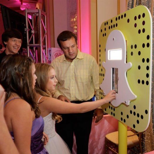 a man and woman standing in front of a snapchat logo phone booth