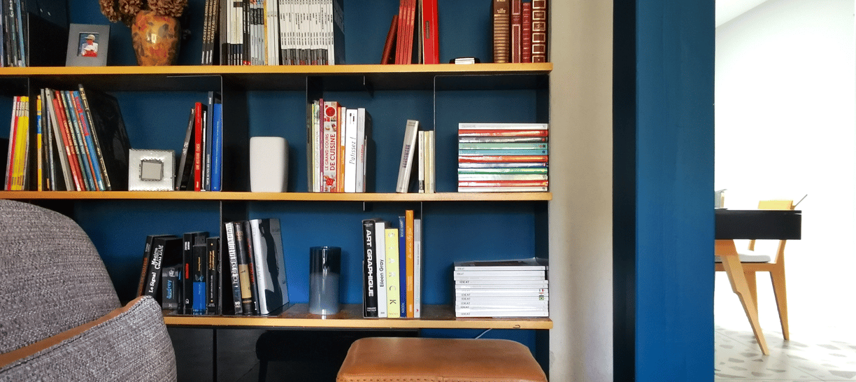 Bibliothèque réalisée avec des étagères en OSB verni, et des séparateurs en métal rouillé vernis.