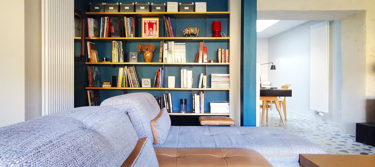 Salon TV avec fauteuil, méridienne et bibliothèque sur mesure en bois et métal. Ouverture sur bureau