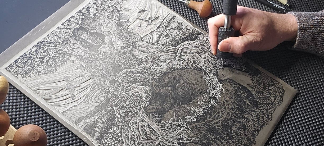 a person is working on a linocut using a fine cutting tool