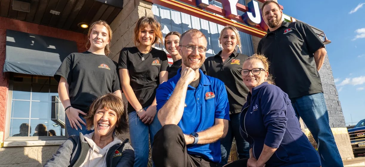 a group of people standing in front of a happy j j's restaurant