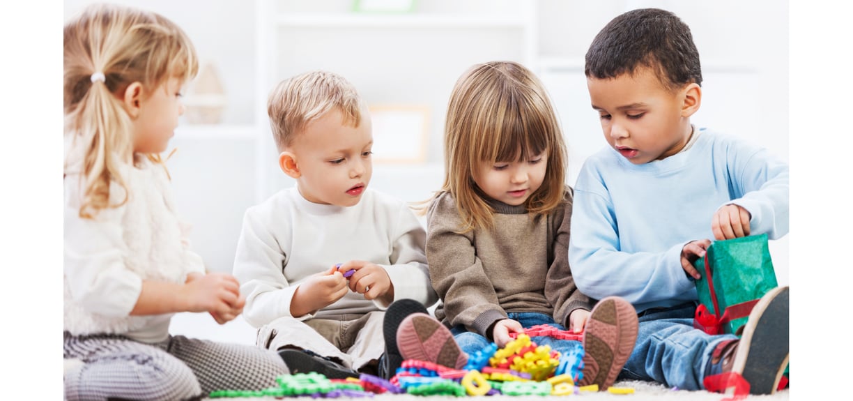 4 young children playing with toys on the floor