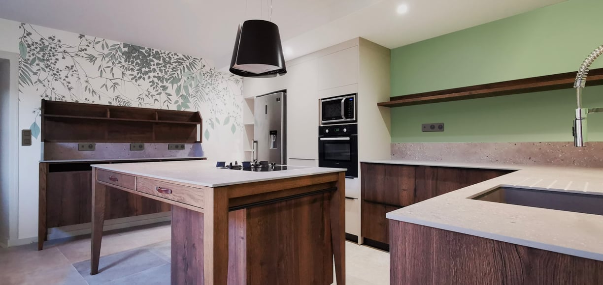 Cuisine en chêne massif avec plan en pierre. Armoire beige anti trace de doigts. Ilot Plaque mixte