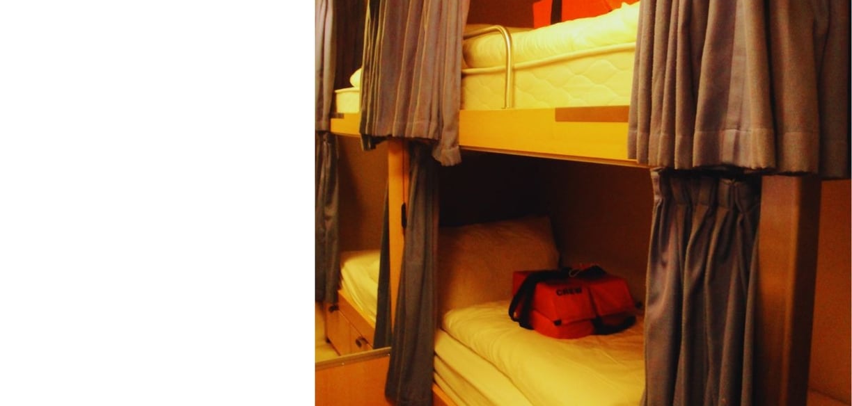 Primeira cabine da autora a bordo, com cama, TV e telefone, oferecendo conforto básico para descanso