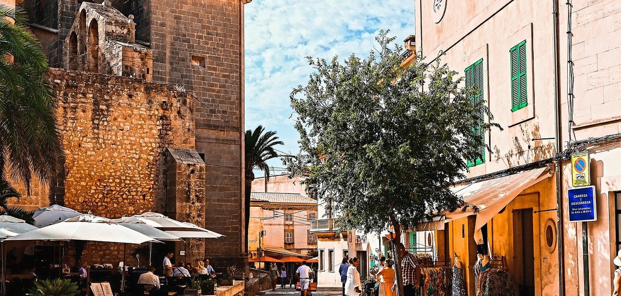 Town in Mallorca with people walking and sitting near an old building