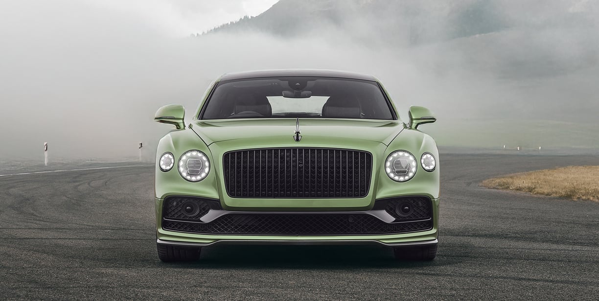 a green bentley flying spur in the swiss mountains