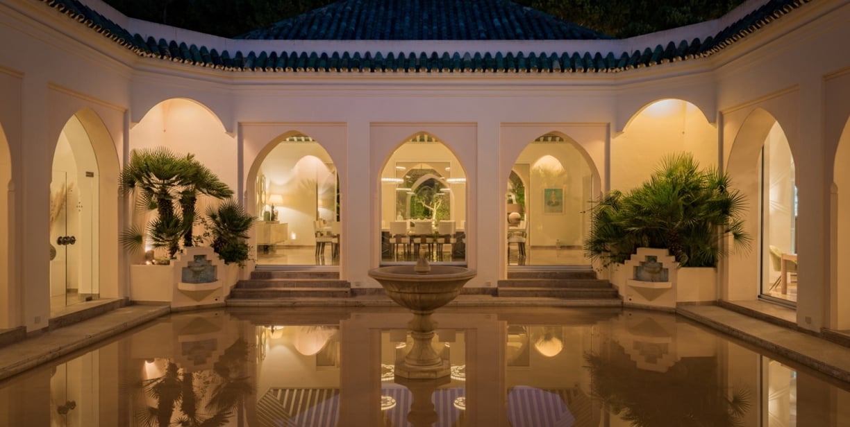 Courtyard at Villa El Rincon featuring a central fountain surrounded by flooded reflective flooring and classic arches.
