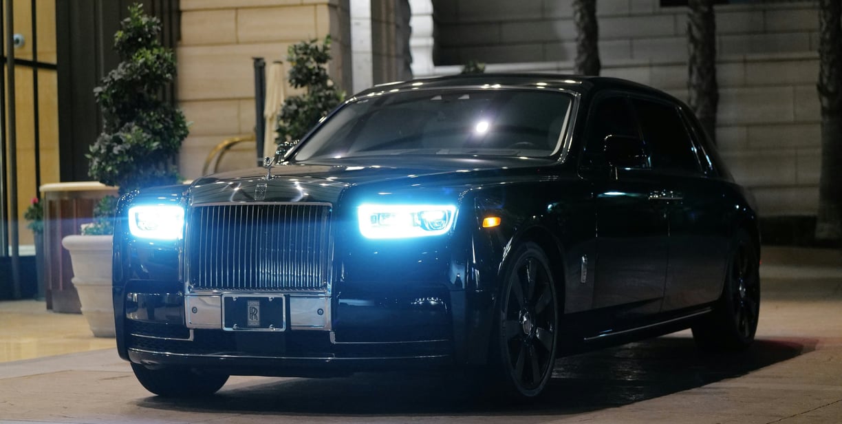 Front side image of a black Rolls Royce parked upon a pavement space