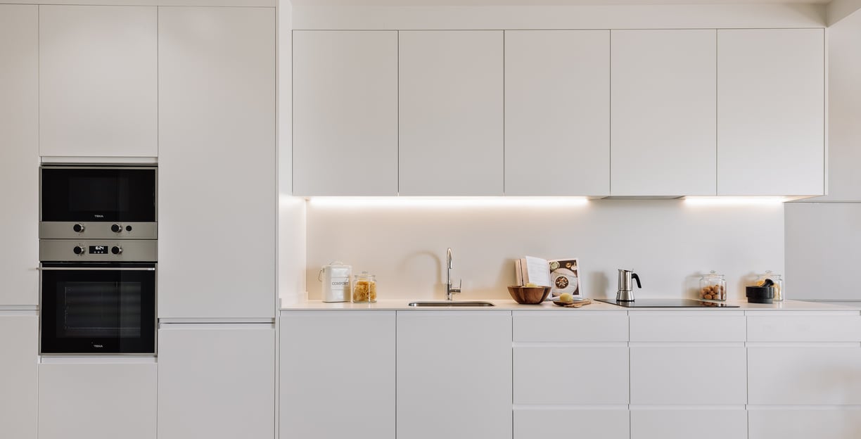 Open-plan kitchen with white cabinets and state-of -the-art appliances for contemporary apartment