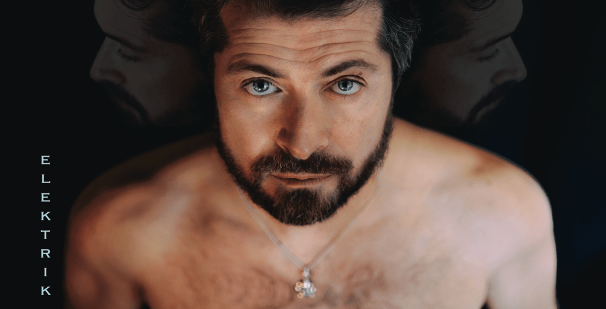 a man with a beard and a necklace on his neck watching at us