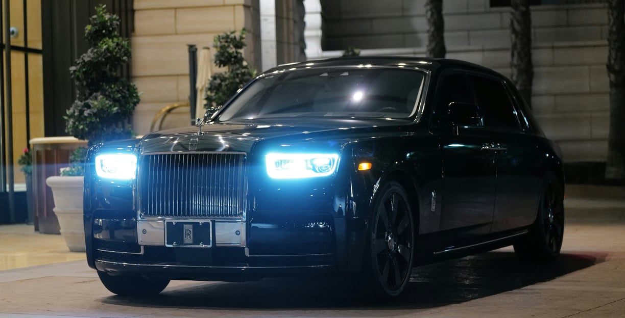 Front side image of a black Rolls Royce parked upon a pavement space