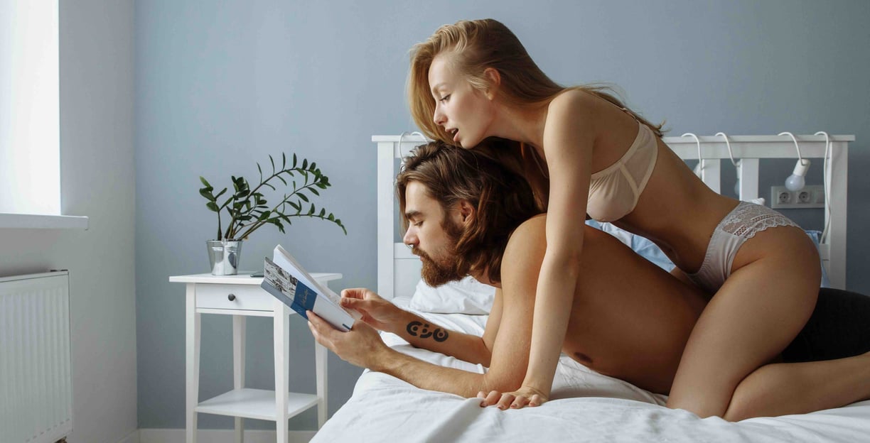 a couple in bed reading about UroFill the superior penis enlargement procedure internationally