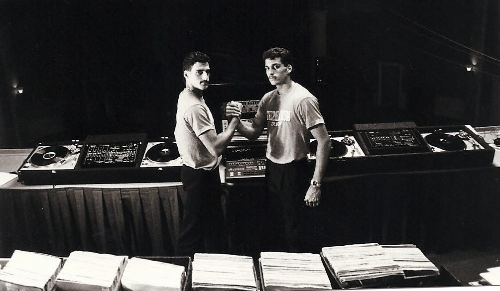 two men standing in front of a table with records